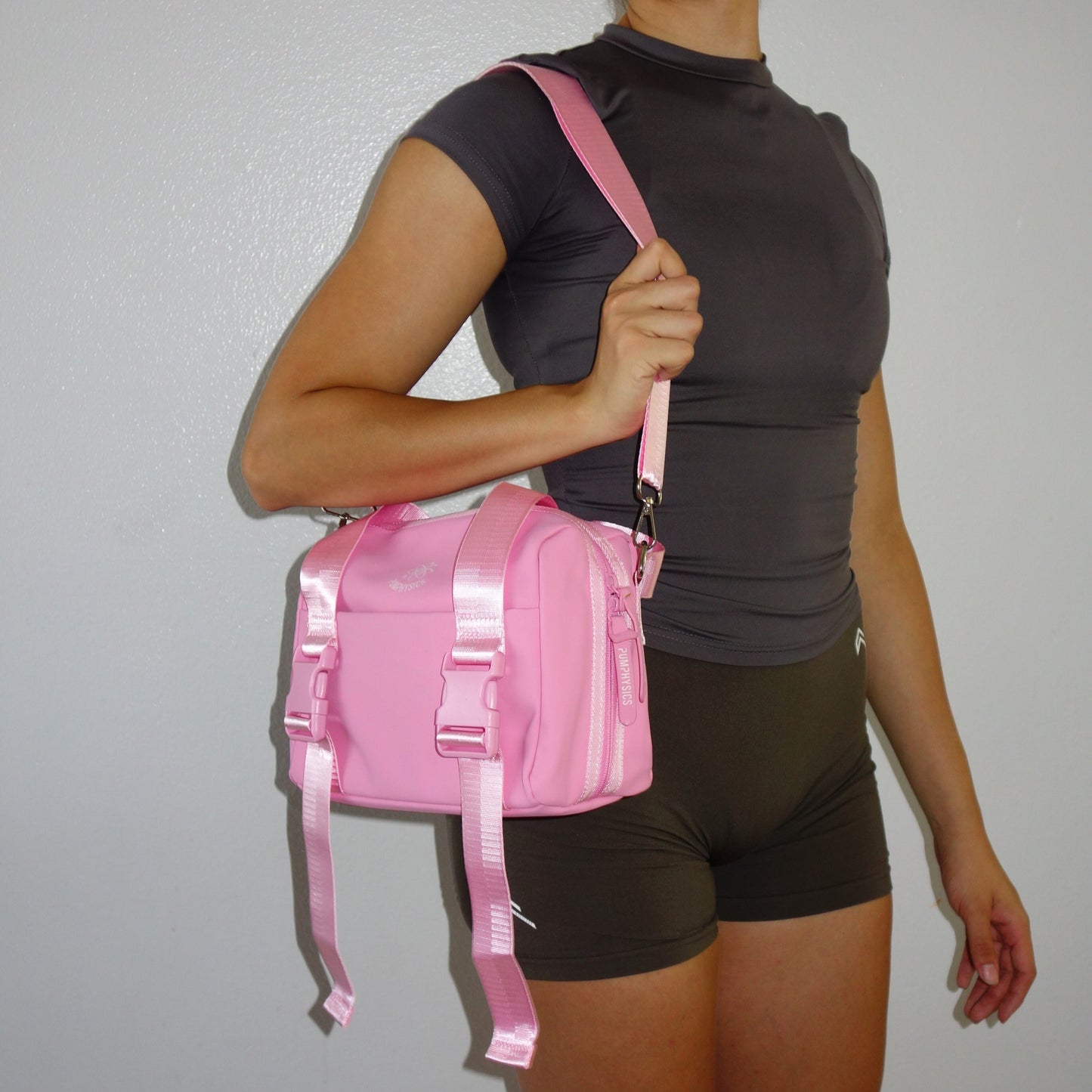 Person wearing a pink mini gym duffel bag against a plain background